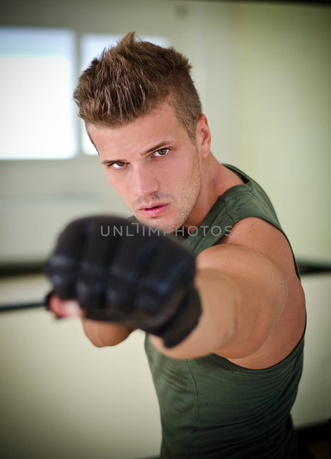 Attractive young man with boxer's gloves throwing a punch towards the camera 