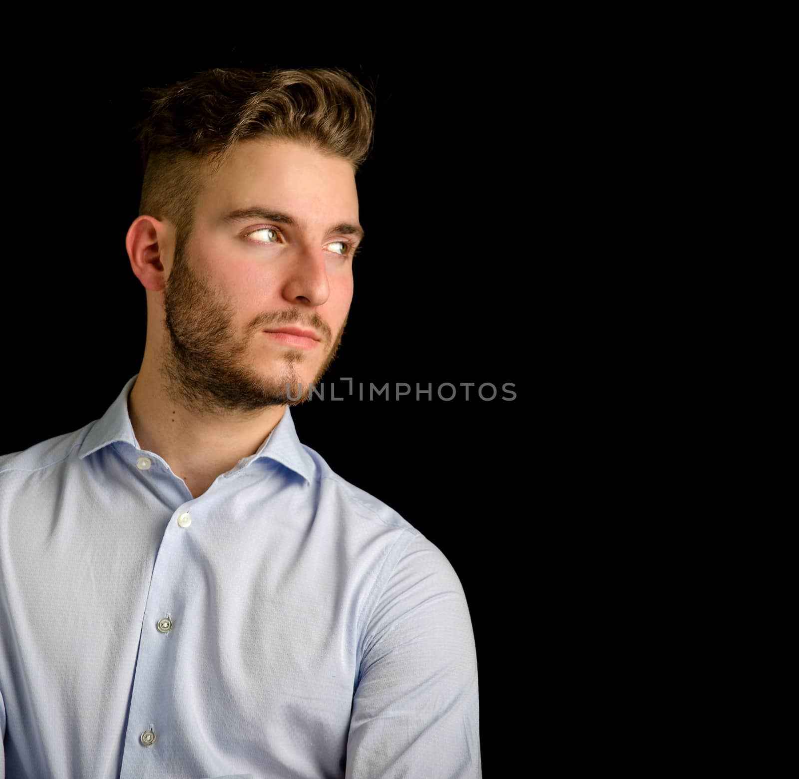 Handsome young man  looking to a side, large copy-space, isolated on black background