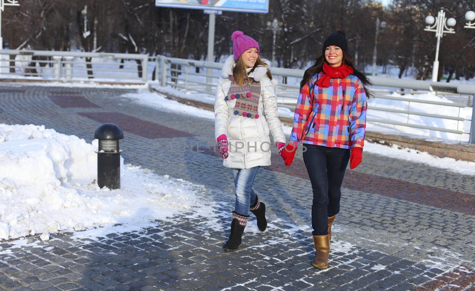 Happy young couple women in winter street by andersonrise