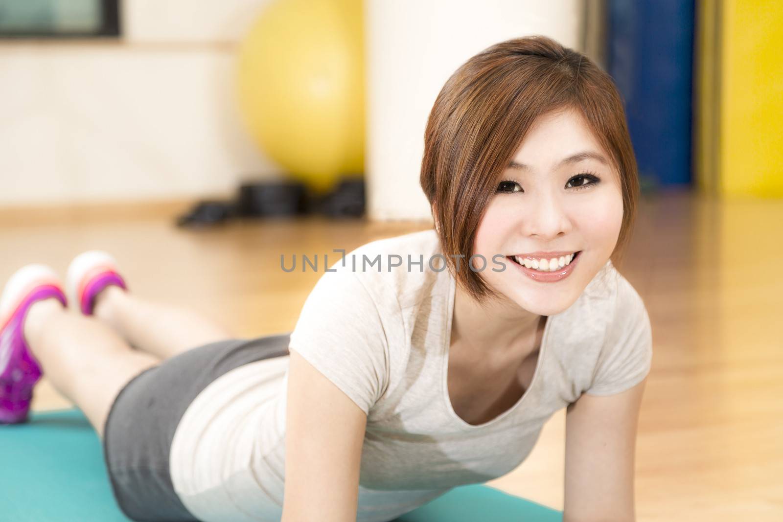 A young Asian woman doing push ups on a mat 