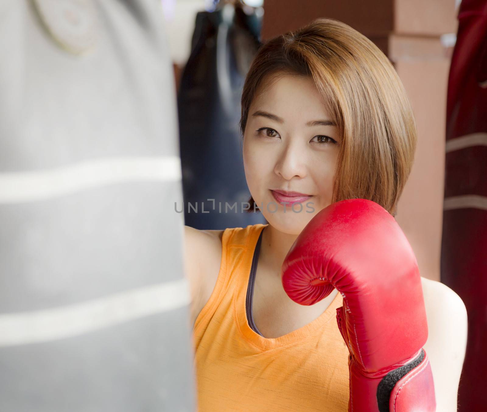 An Asian lady waring red glove practicing boxing.