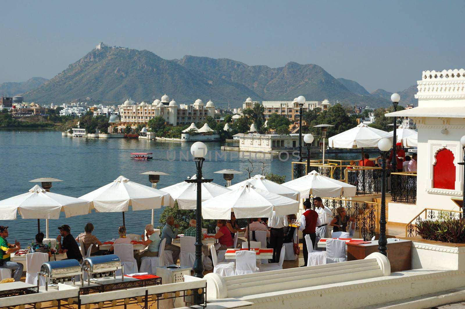UDAIPUR,RAJASTHAN,INDIA - NOVEMBER 19: tourists enjoying the beautiful view of Pichola lake at restaurant on the embankment of Udaipur city,so called "India Venice", on November 19,2012 in Udaipur,Rajasthan,Ukraine