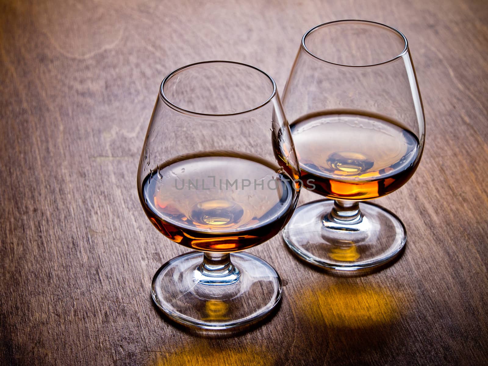 Two glasses of cognac on a wooden table