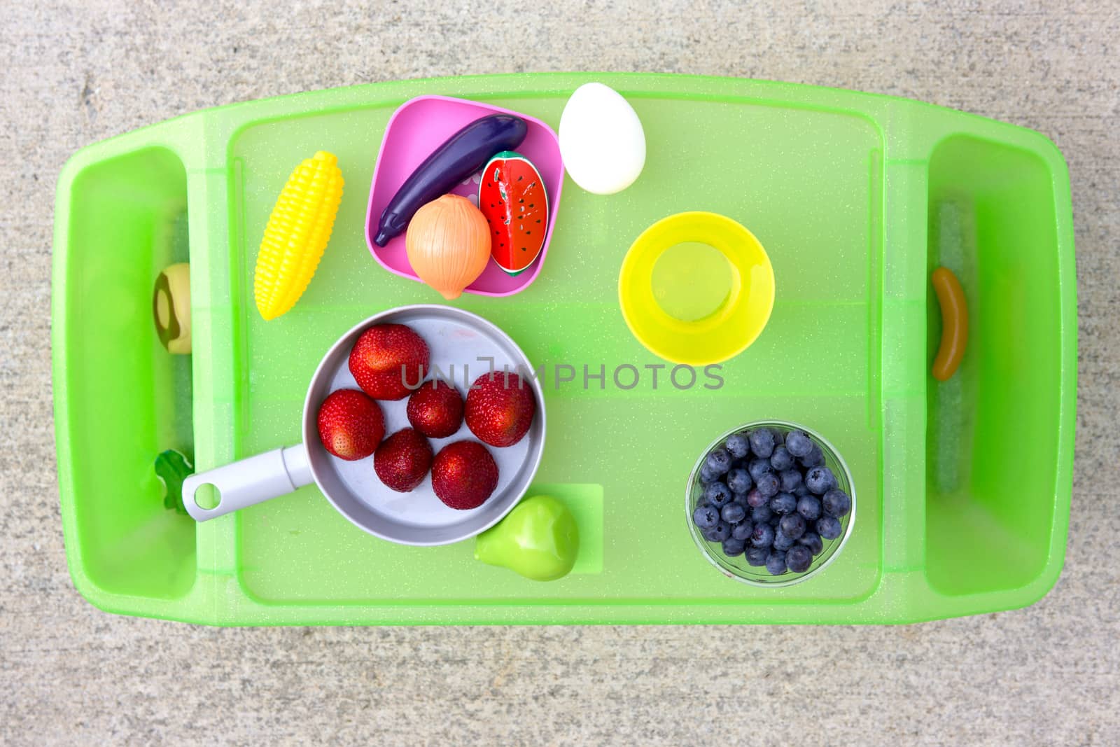 Little girls play and eat time tray with fake toy foods as well as strawberries and blueberries