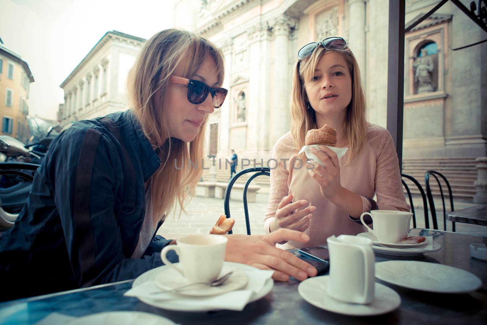 two beautiful blonde women talking at the bar in the city