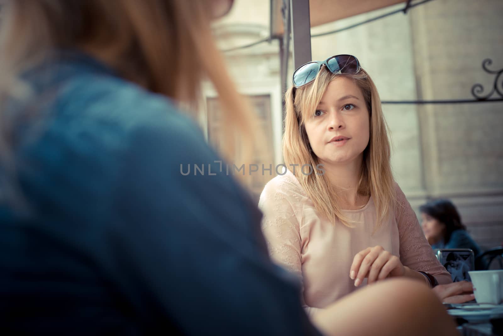 two beautiful blonde women talking at the bar in the city