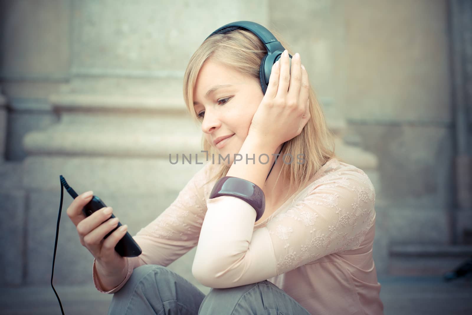 beautiful blonde woman listening to music in the city