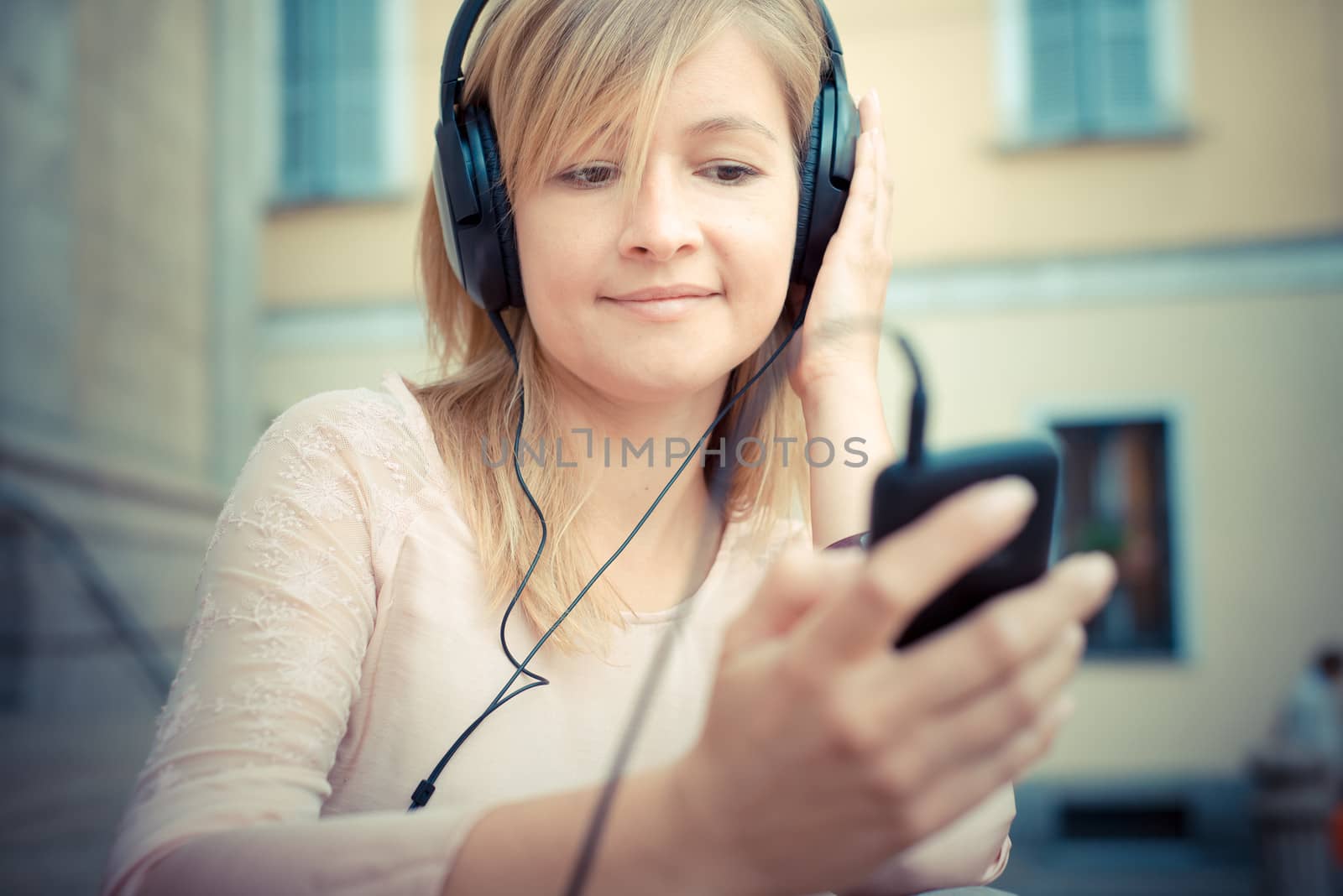 beautiful blonde woman listening to music in the city