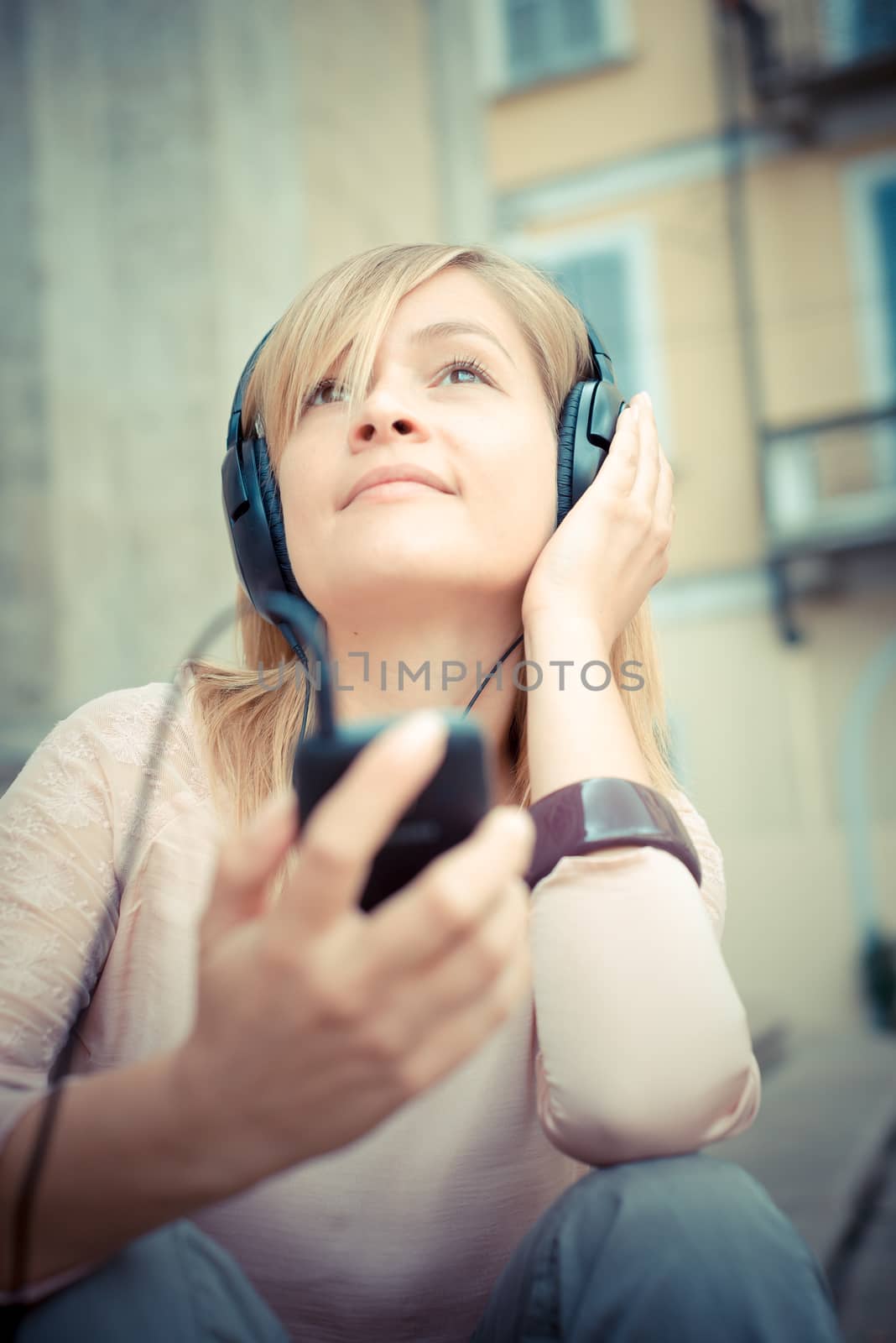 beautiful blonde woman listening to music in the city