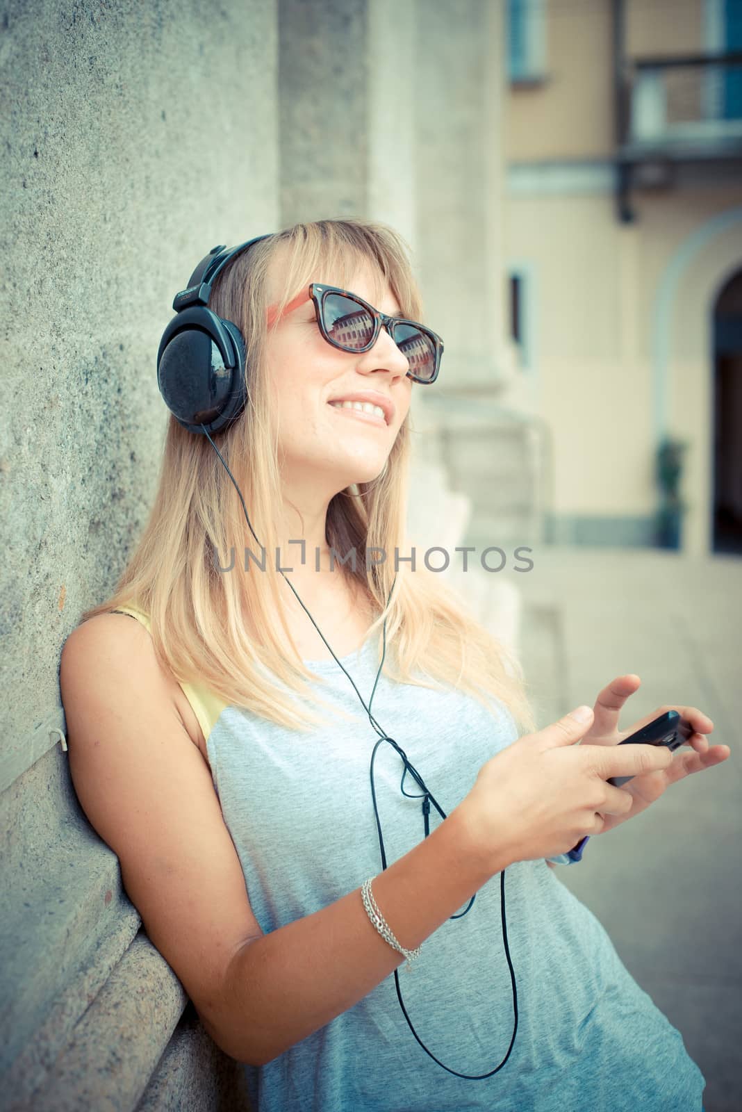 beautiful blonde woman listening to music in the city