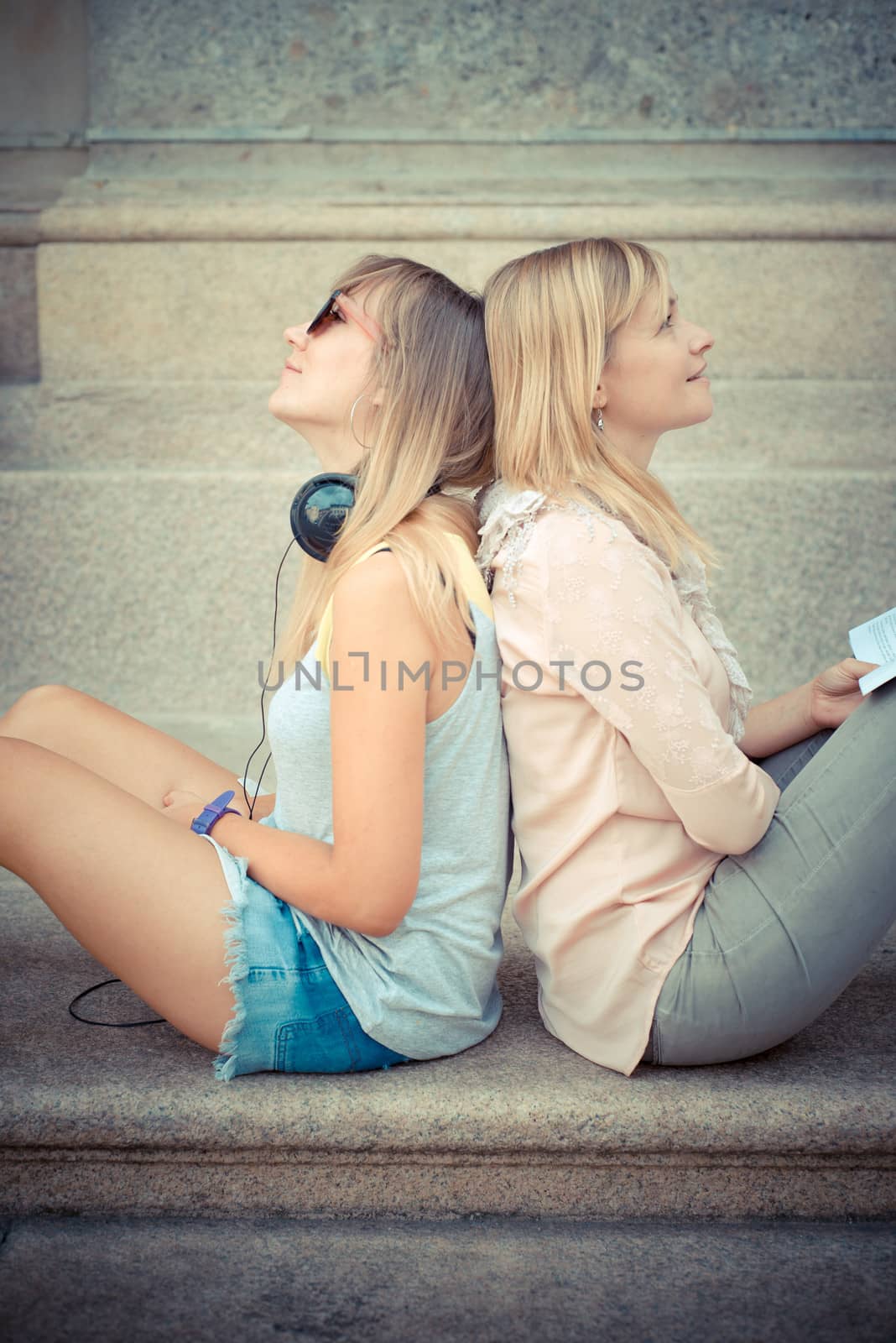 two beautiful blonde woman relaxing by peus