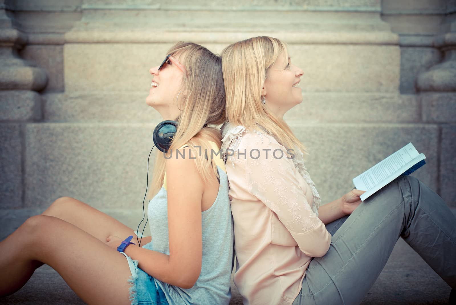 two beautiful blonde woman relaxing by peus