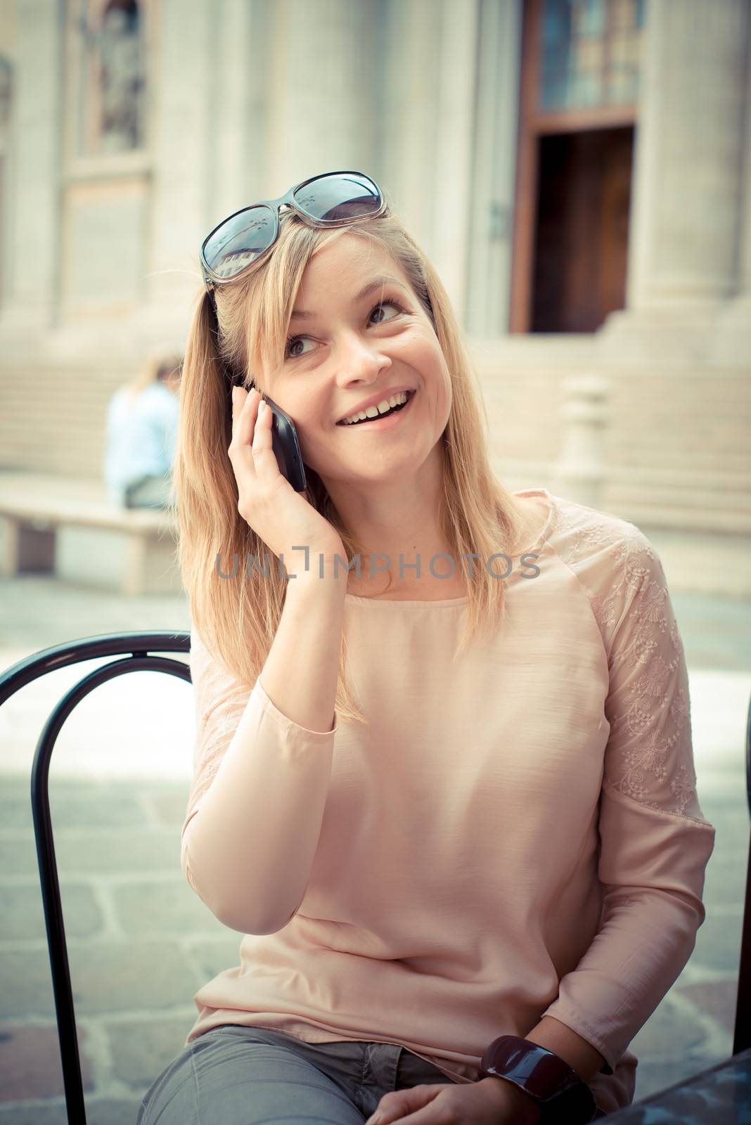 beautiful blonde woman on the phone at the bar in the city