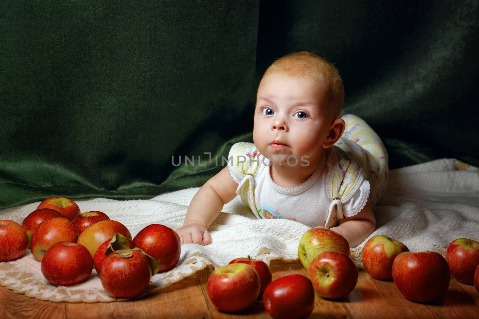 Redhead babe lying among ripe apple and smiling at the camera