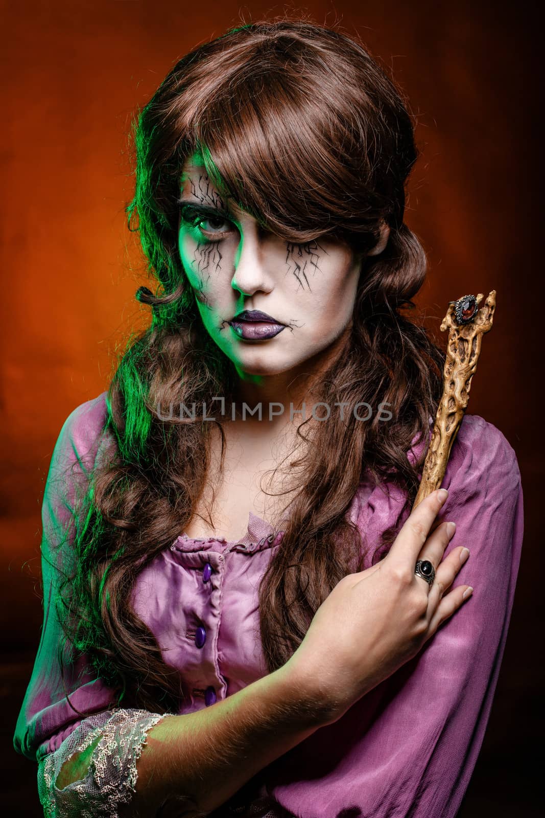 Girl in the image of a witch with a magic wand shot in studio