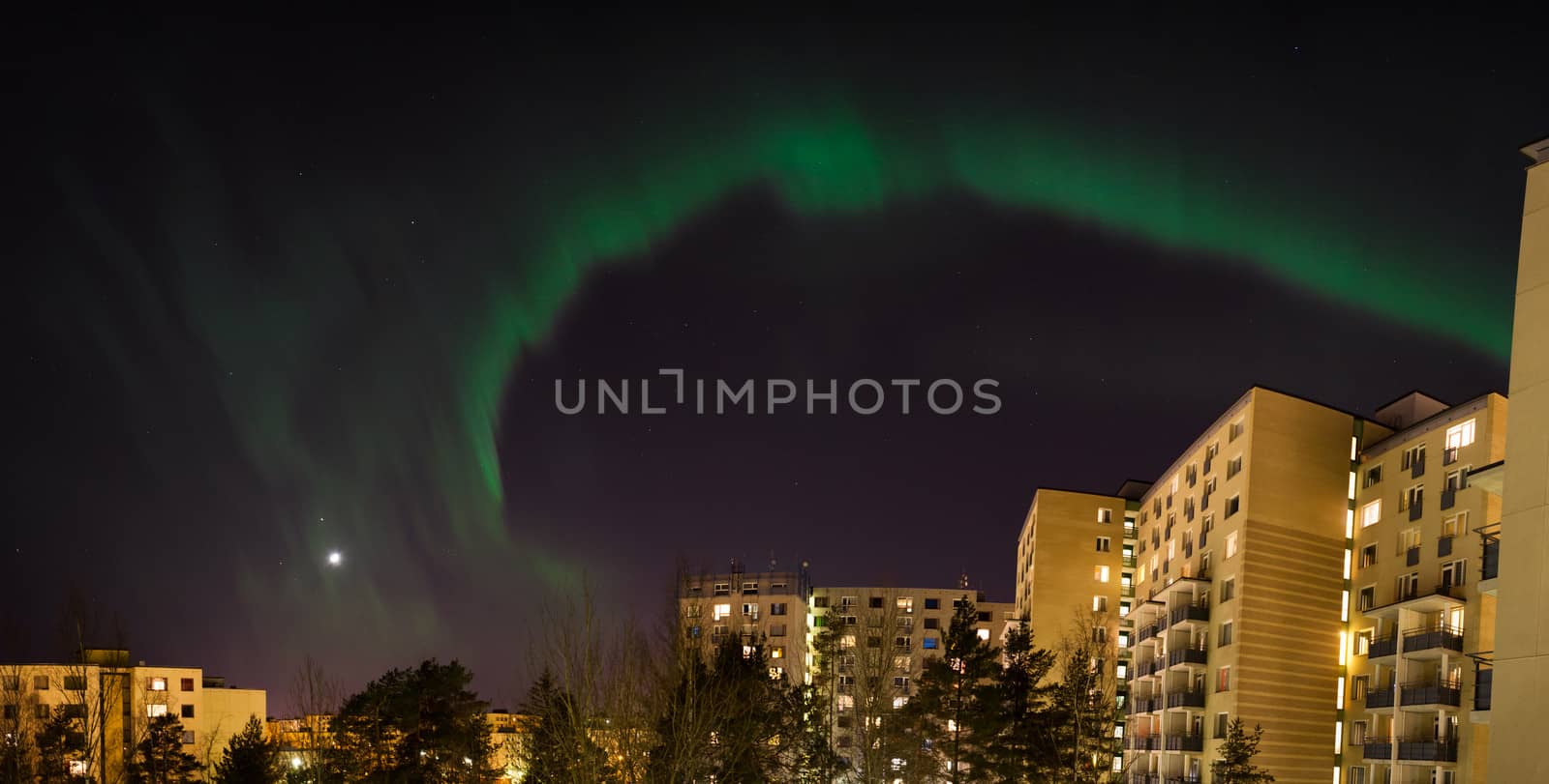 Green aurora borealis over city buildings
