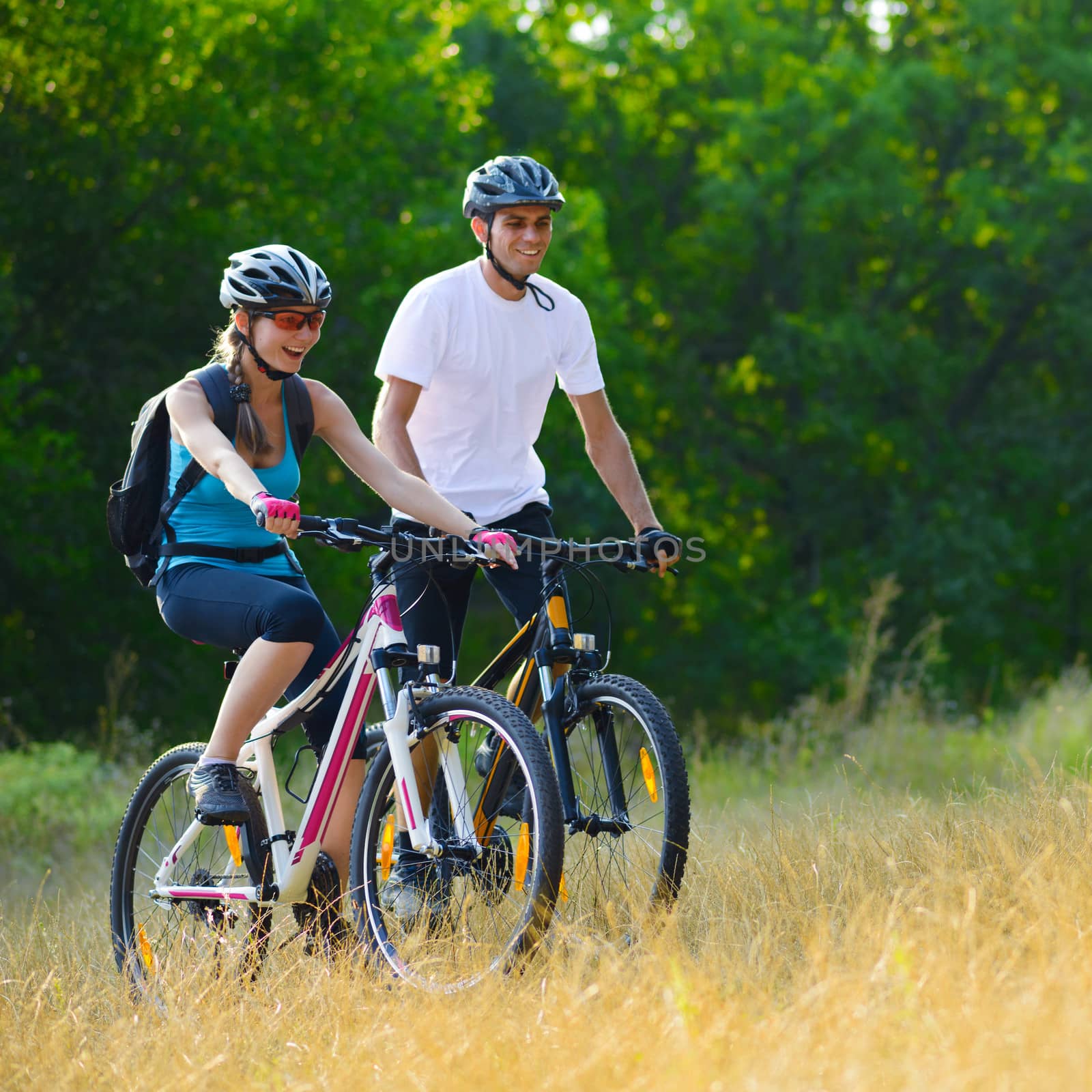 Young Happy Couple Riding Mountain Bikes Outdoor by maxpro