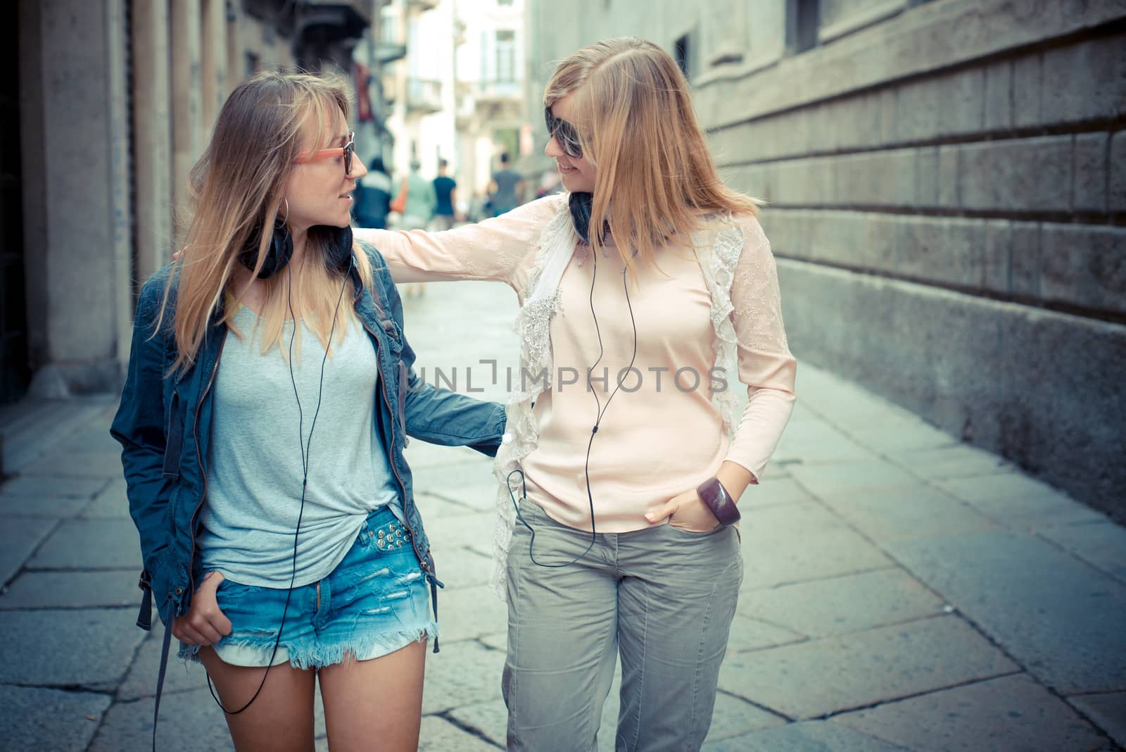two beautiful blonde women walking and talking in the city