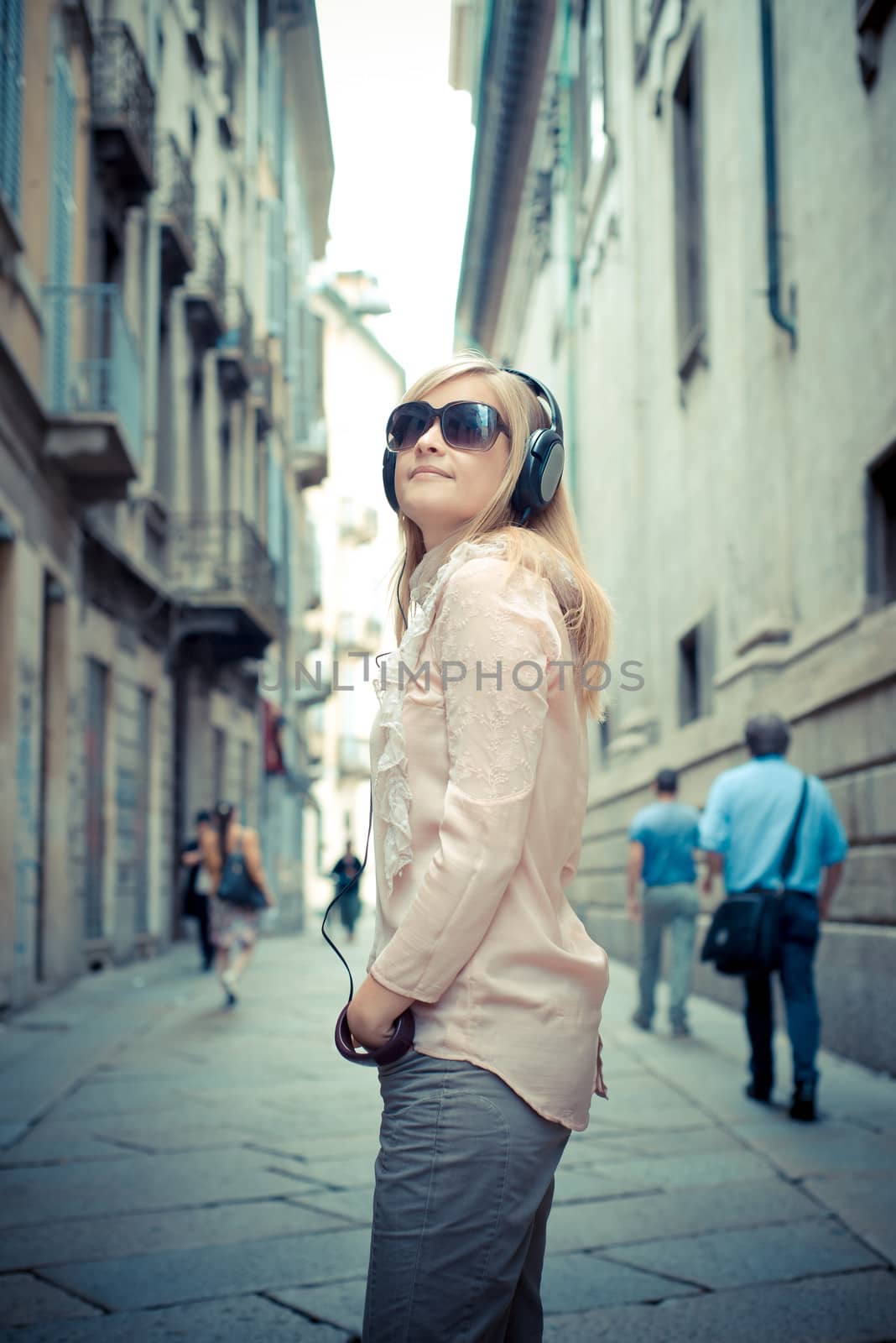 beautiful blonde woman listening to music in the city