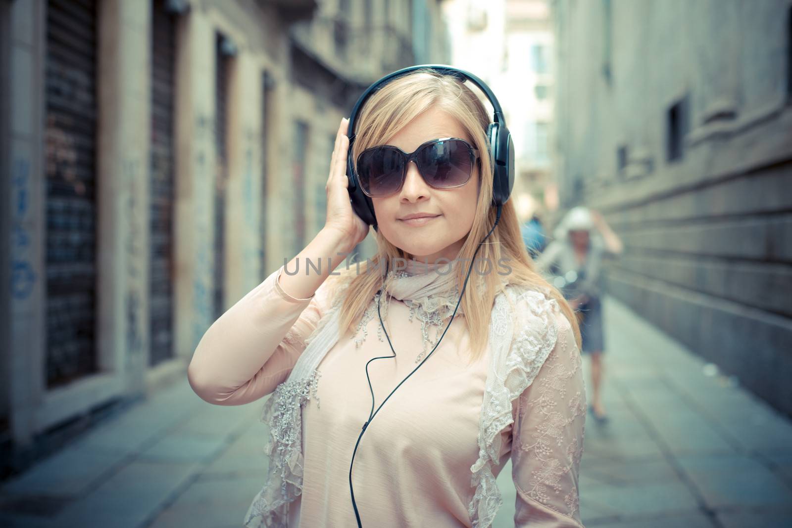 beautiful blonde woman listening to music in the city