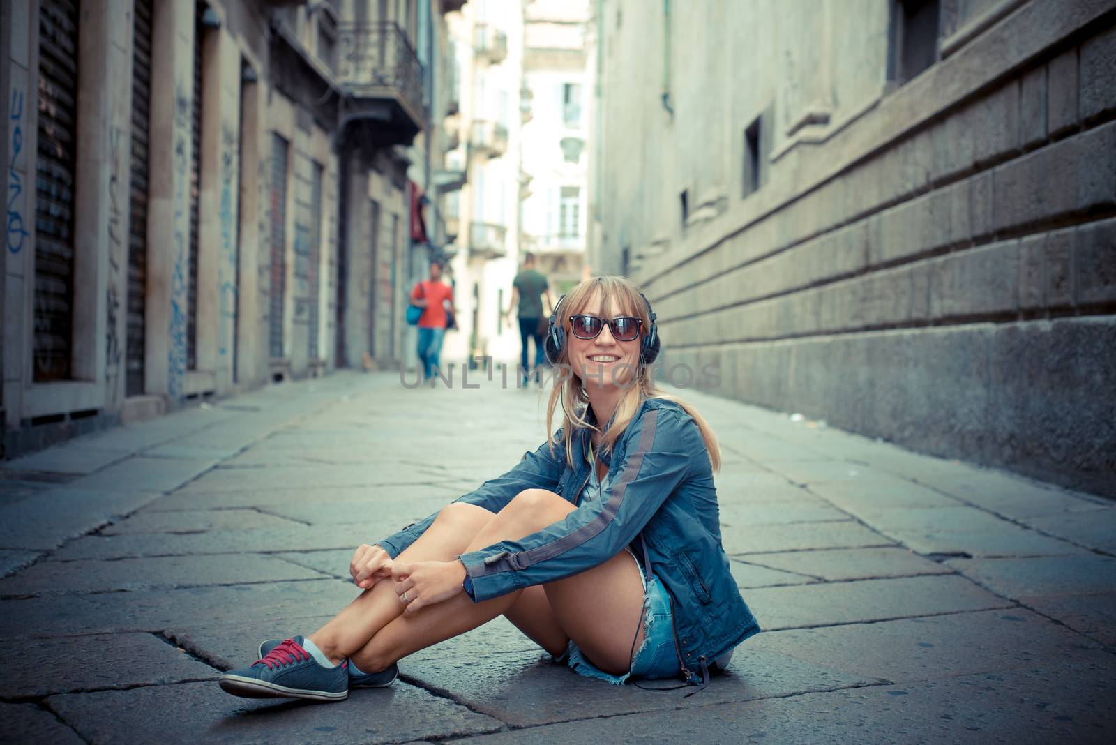 beautiful blonde woman listening to music in the city