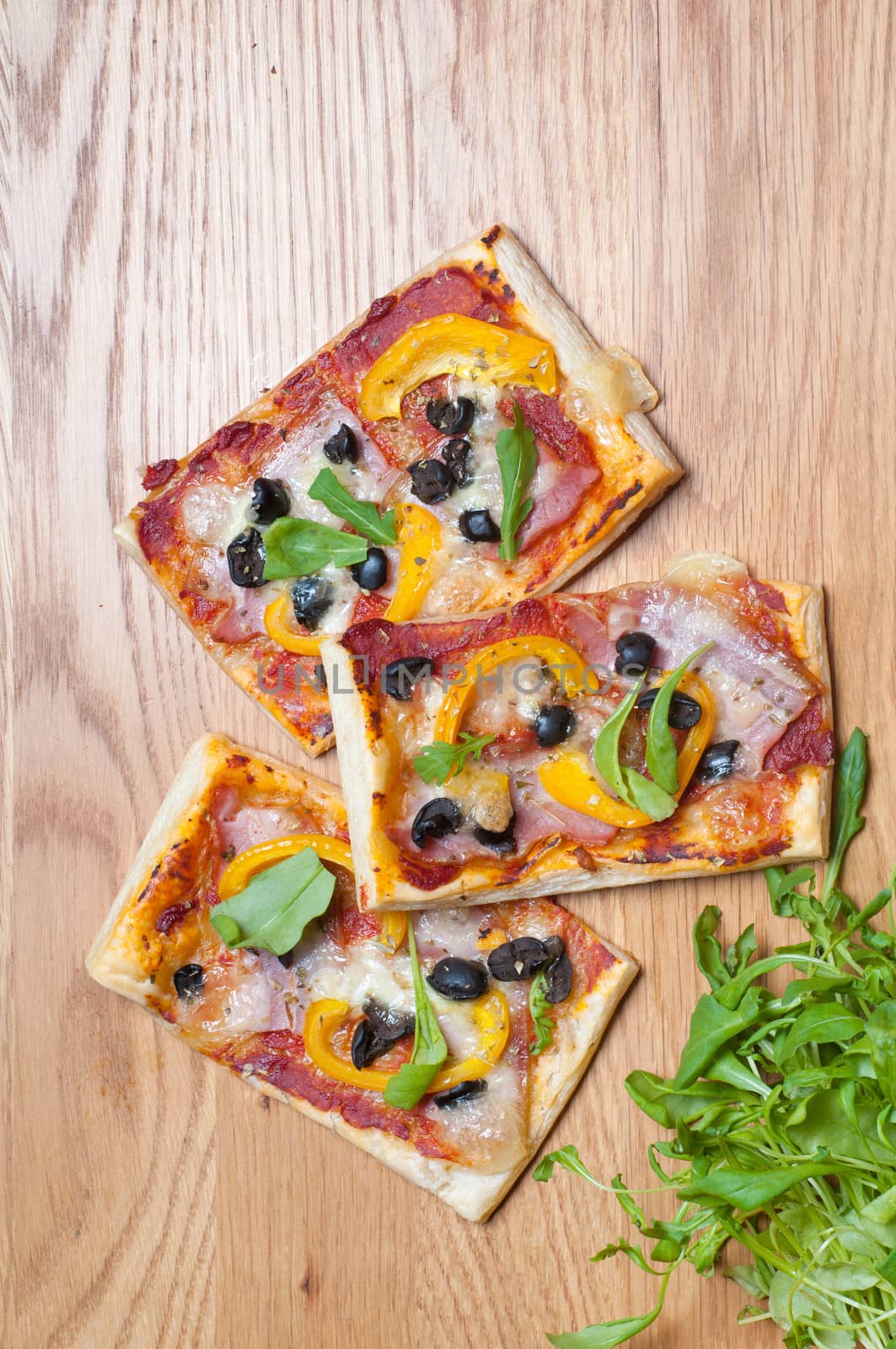 Puff pastry cake with ruccola and olives on the wooden table