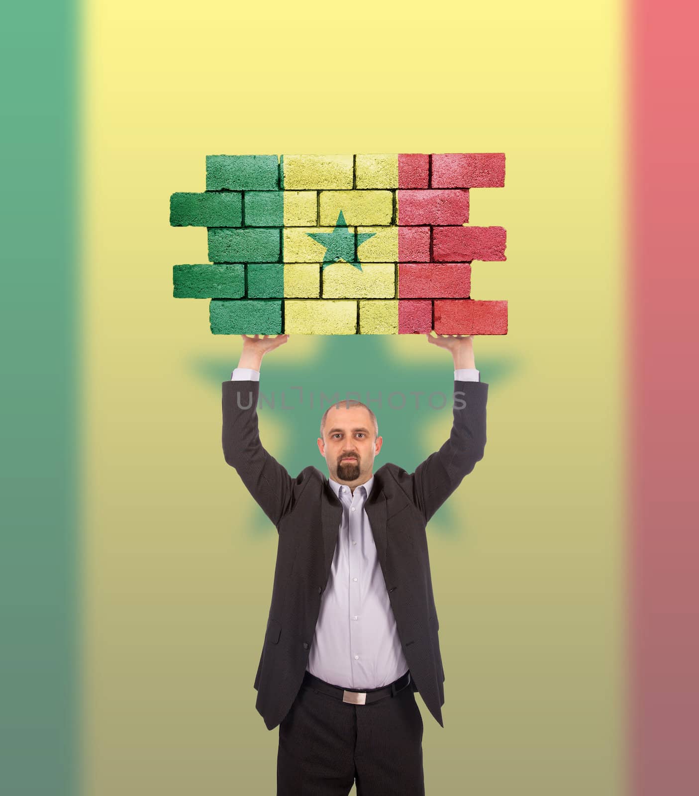 Businessman holding a large piece of a brick wall, flag of Senegal, isolated on national flag