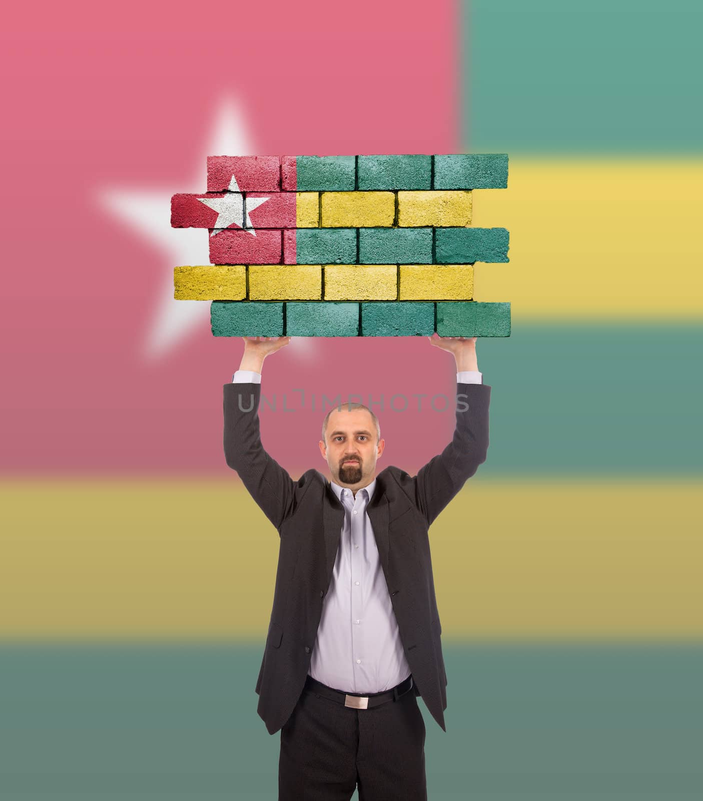 Businessman holding a large piece of a brick wall, flag of Togo, isolated on national flag