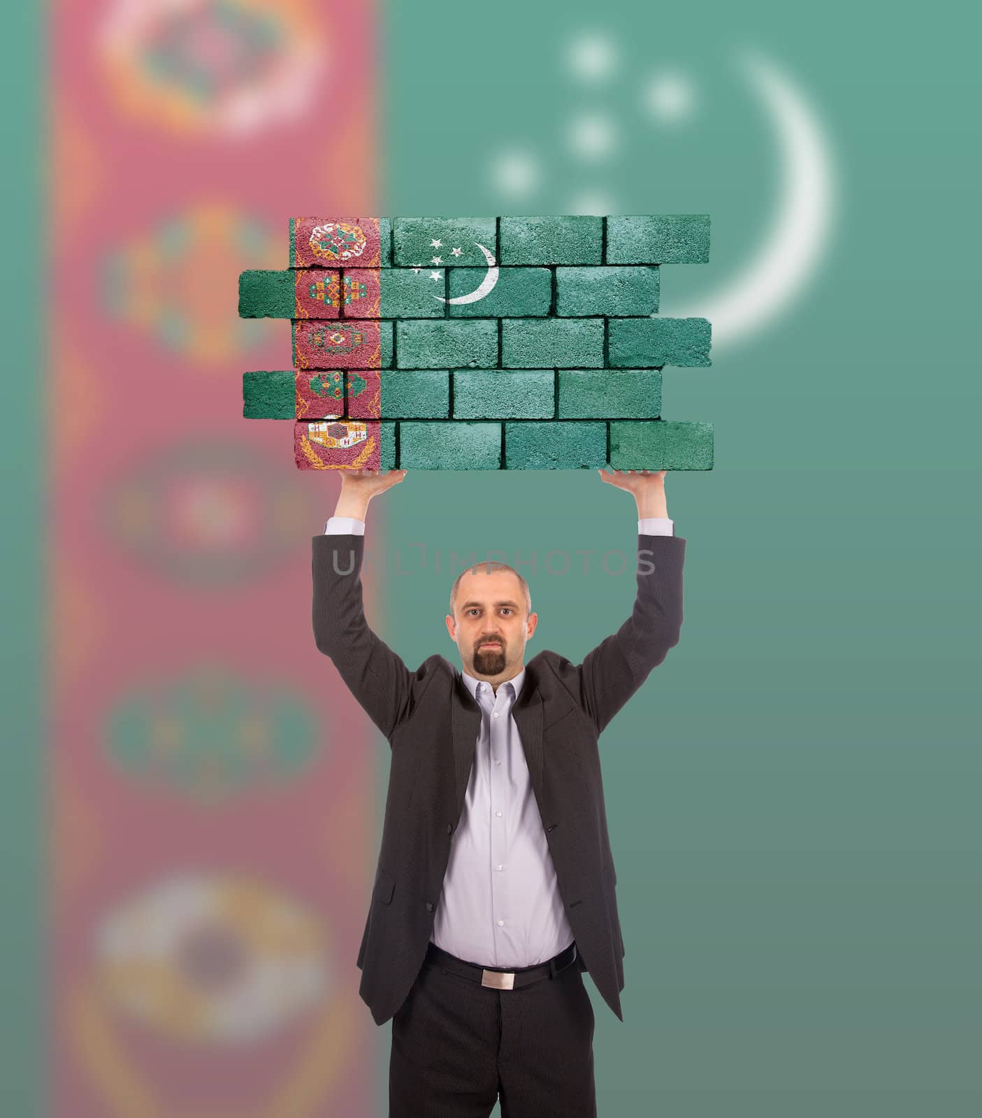 Businessman holding a large piece of a brick wall, flag of Turkmenistan, isolated on national flag