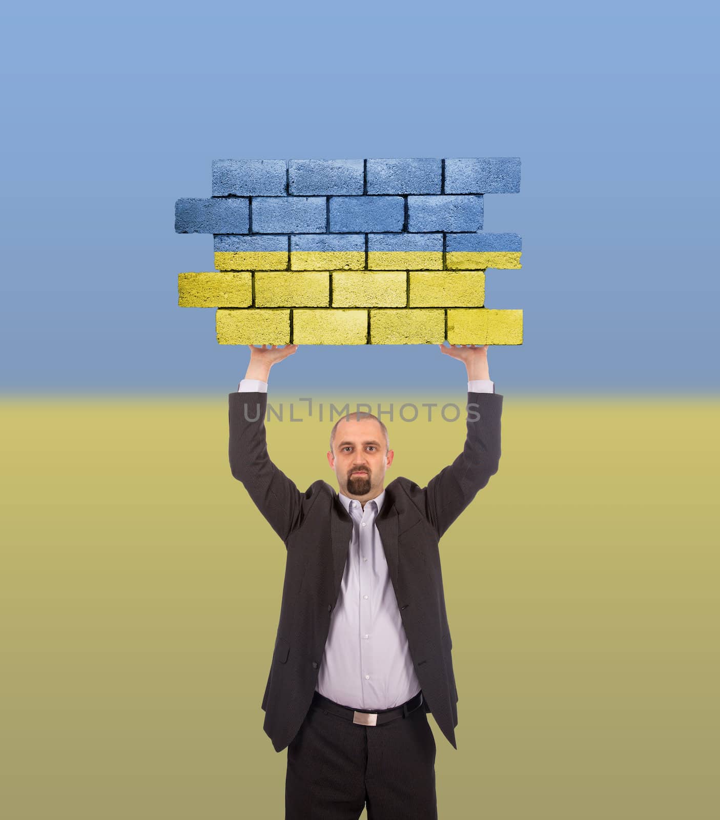 Businessman holding a large piece of a brick wall by michaklootwijk