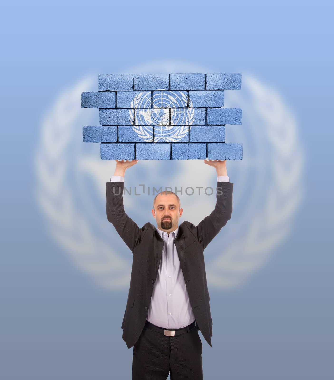Businessman holding a large piece of a brick wall, flag of the United Nations, isolated on national flag