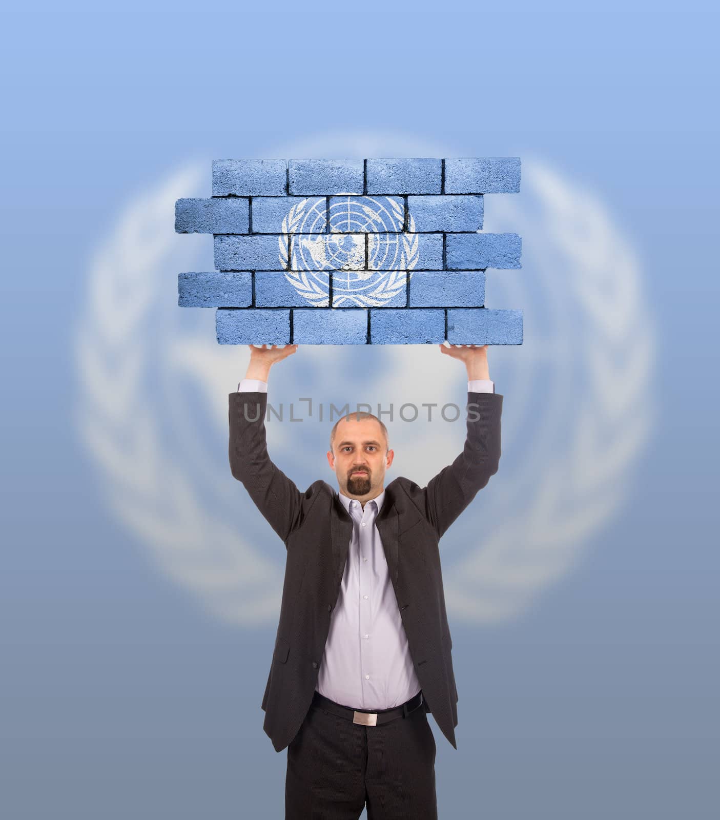 Businessman holding a large piece of a brick wall by michaklootwijk