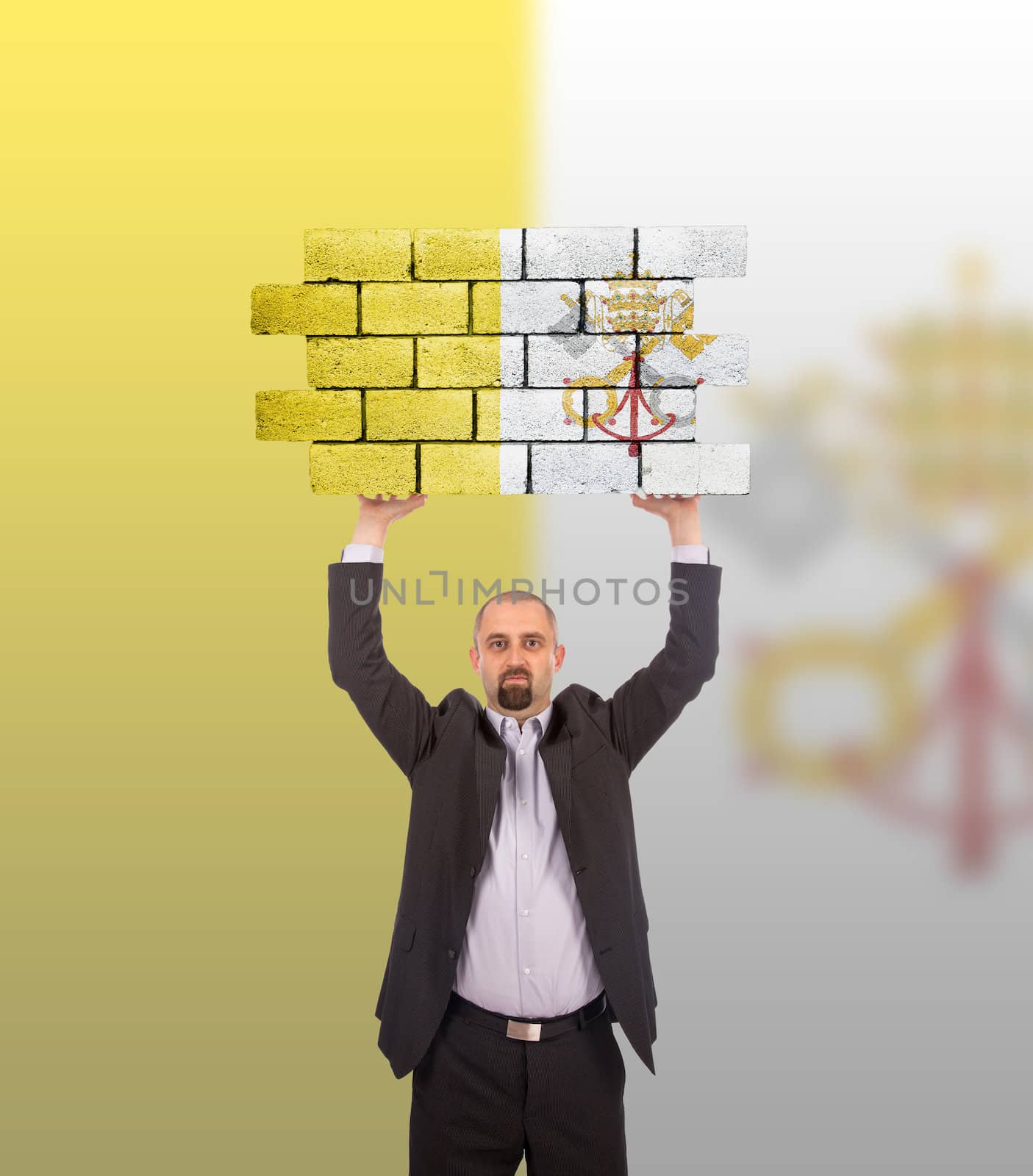 Businessman holding a large piece of a brick wall, flag of Vatican City, isolated on national flag