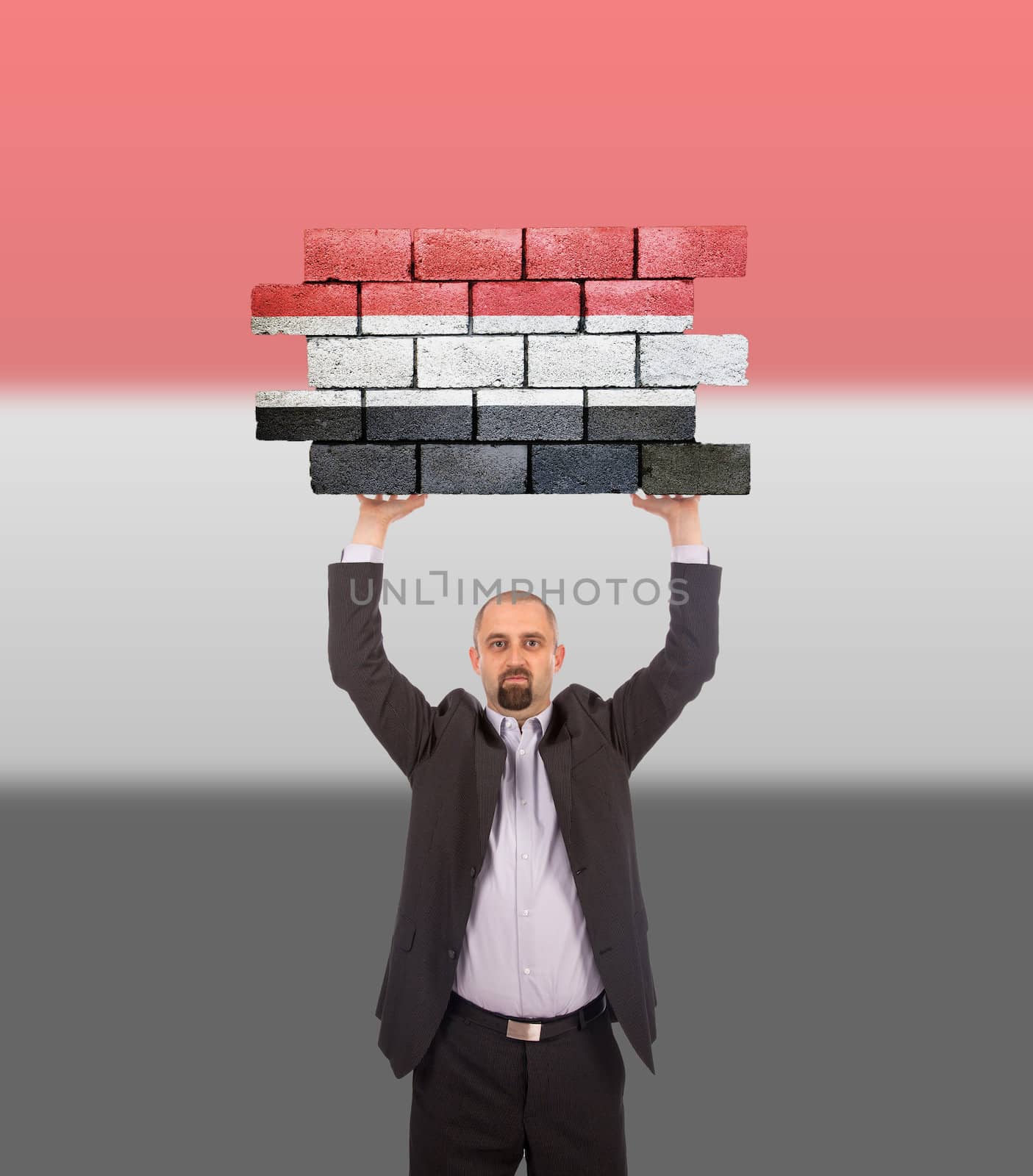 Businessman holding a large piece of a brick wall by michaklootwijk