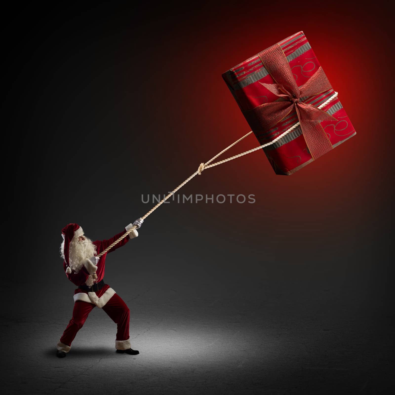Santa Claus pulls a rope with a red box with a gift