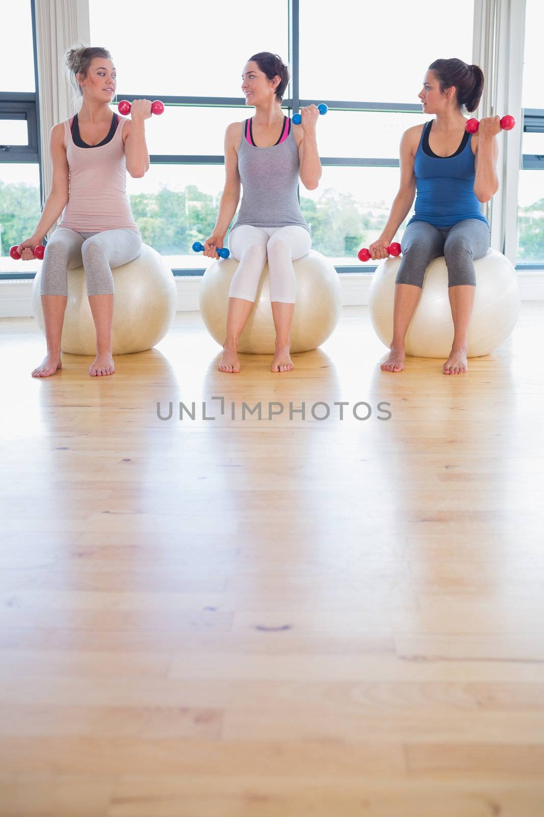 Women lifting weights on exercise balls while talking