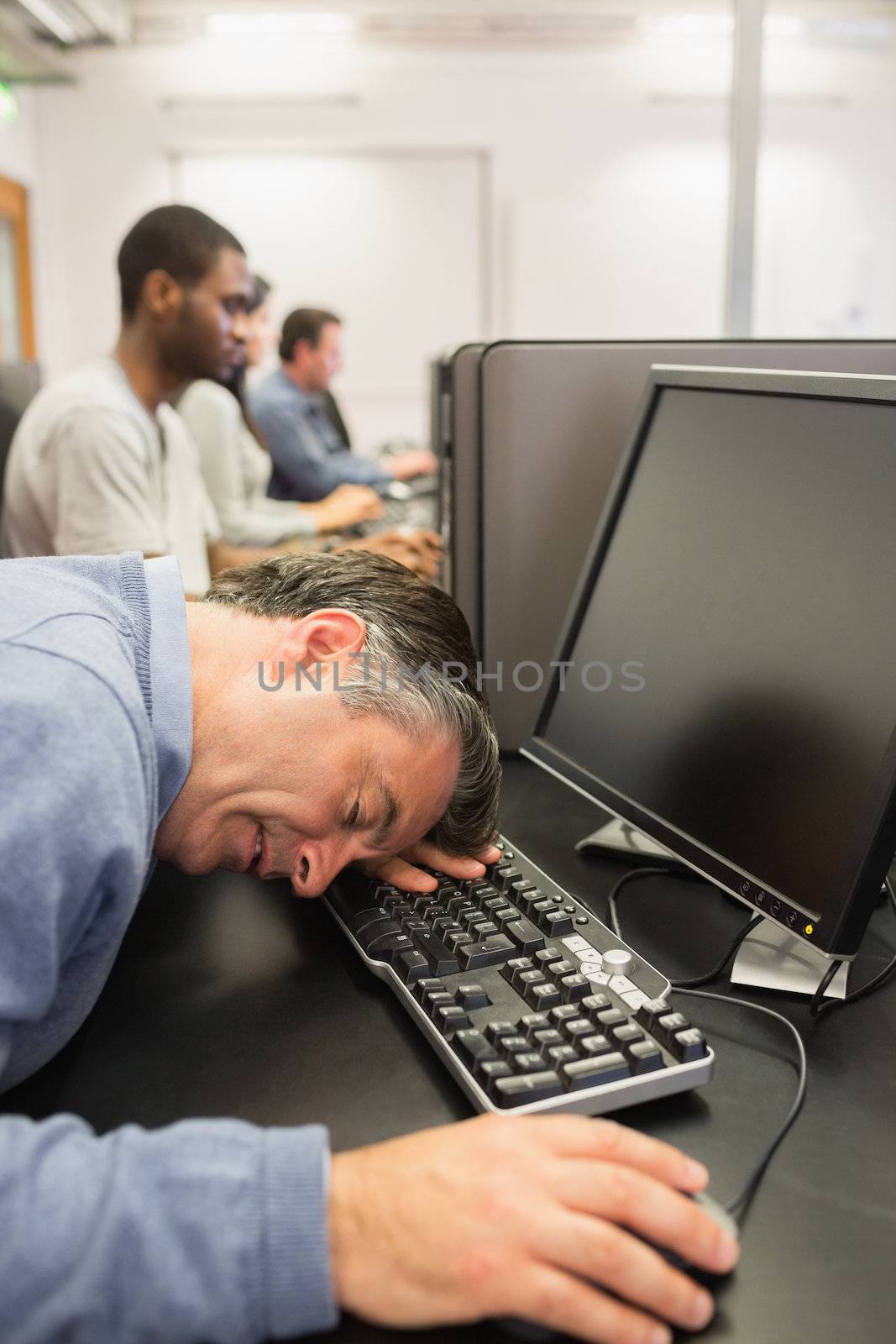 Man sitting sleeping at the keyboard in computer class