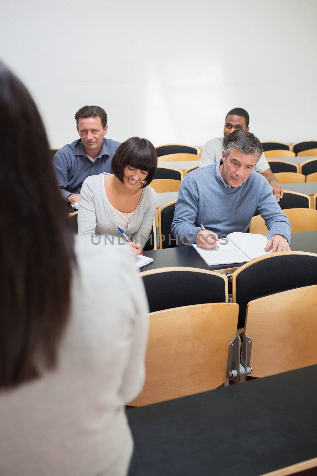 Mature students taking notes in a lecture in college