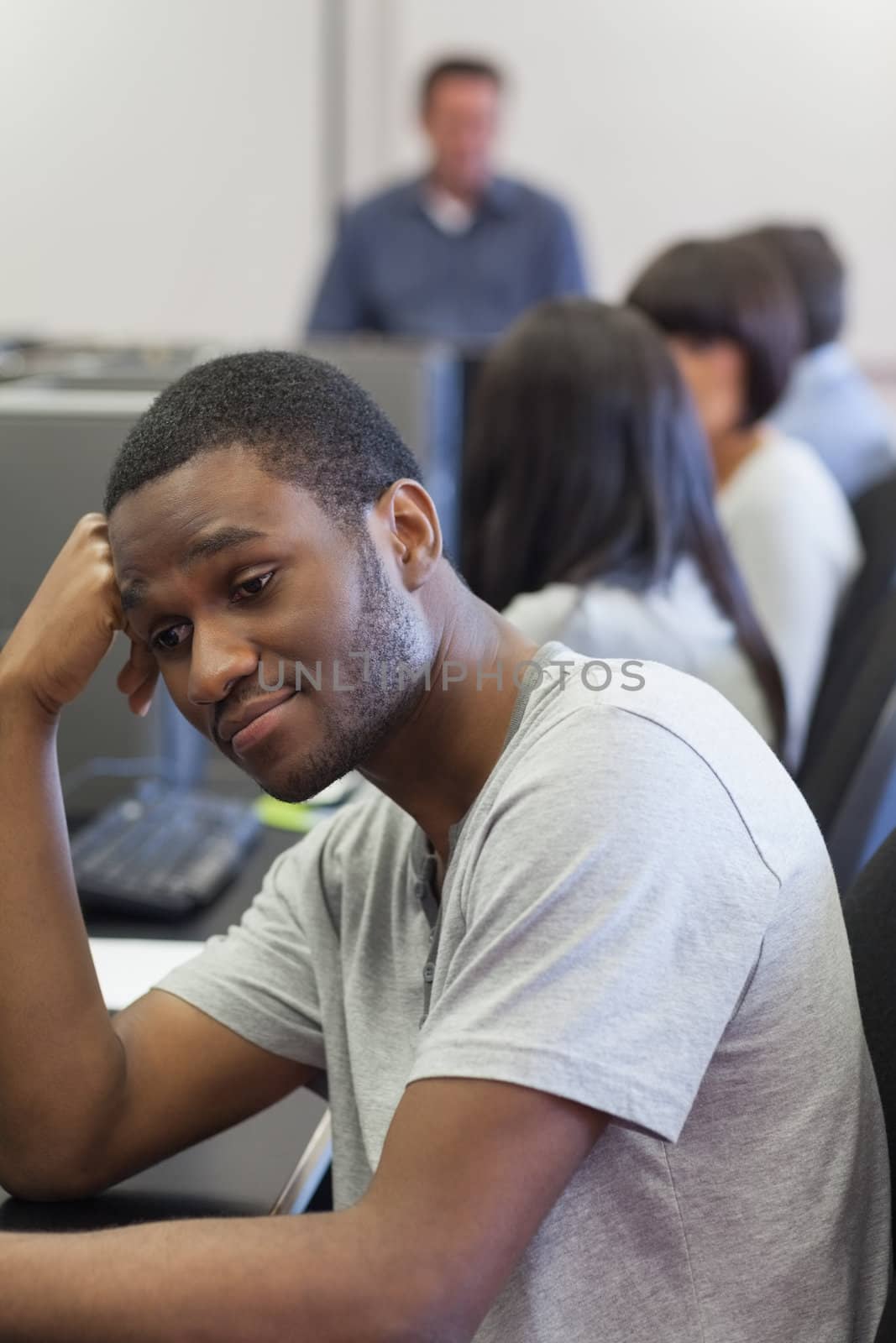 Man turning away and leaning on desk in computer class in college