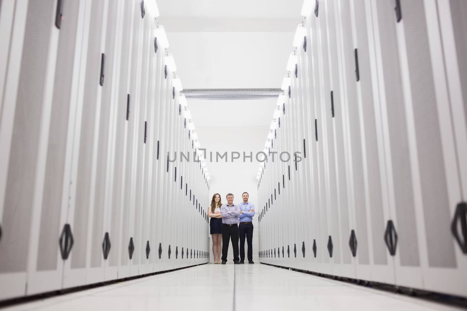 Three techncians standing at end of server hallway in data center