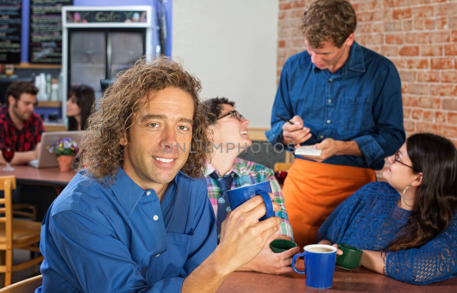 Smiling Caucasian man with friends and server in cafe