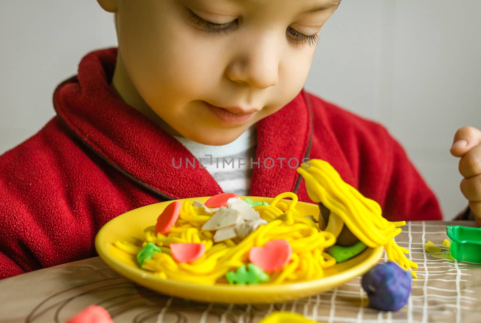 Cute child looking his original spaghetti dish, made with colorful plasticine