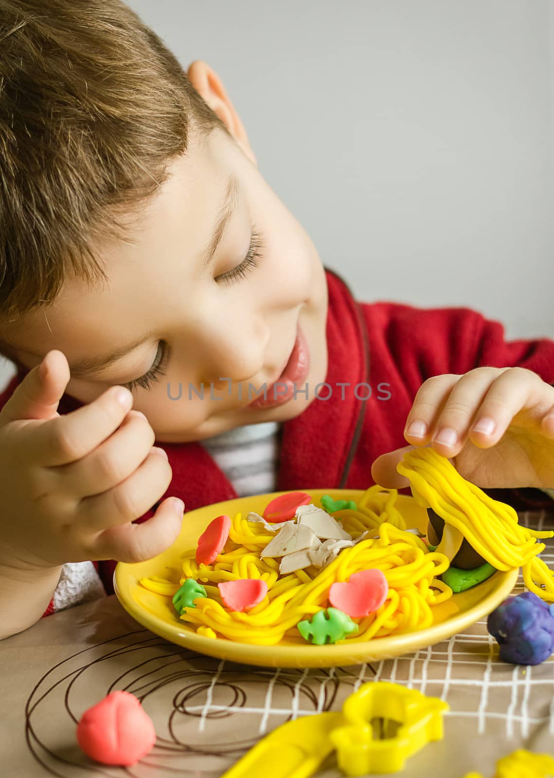 Cute child playing with his original spaghetti dish, made with colorful plasticine