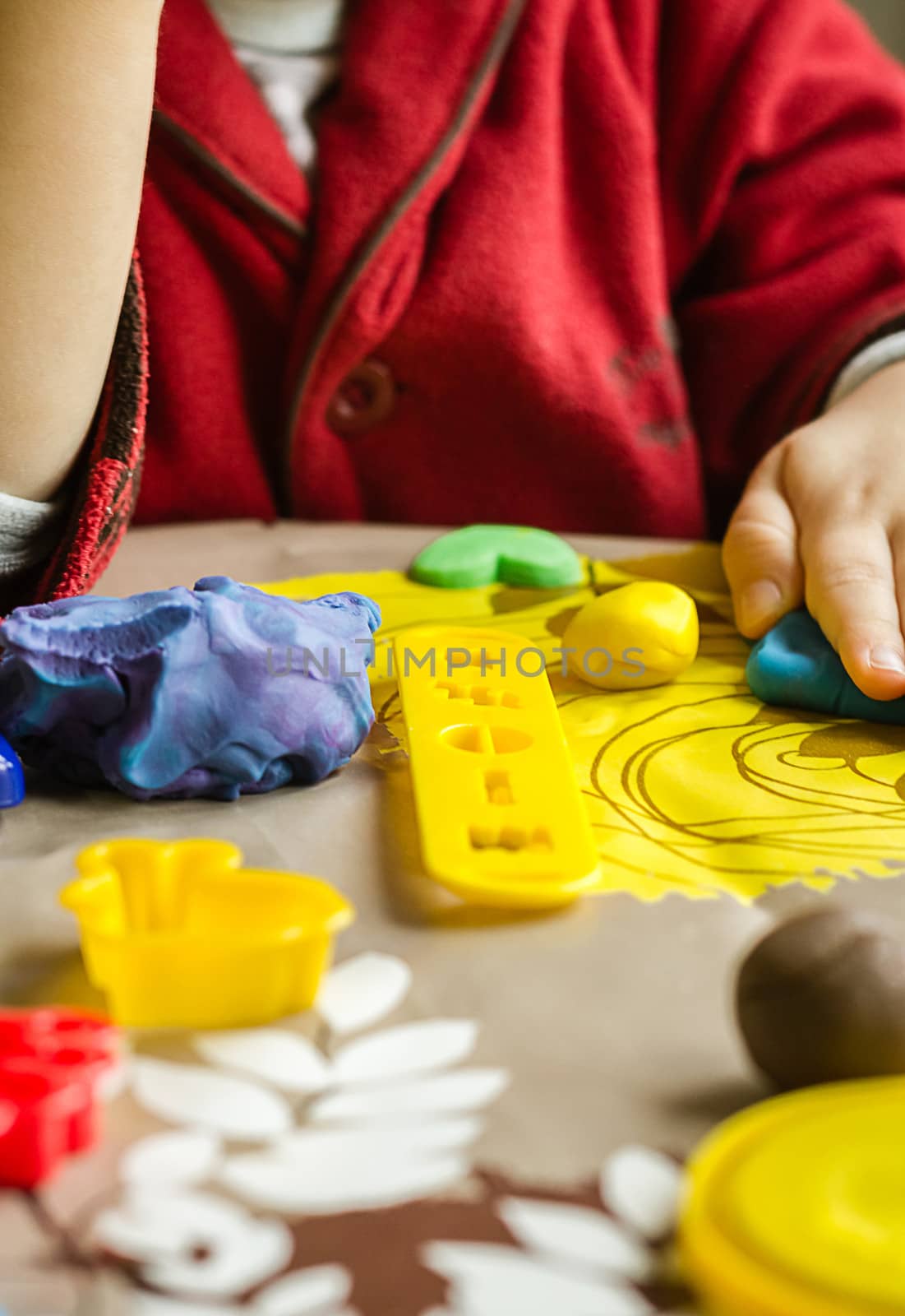 Closeup of colorful plasticine molds and child hands playing on the background