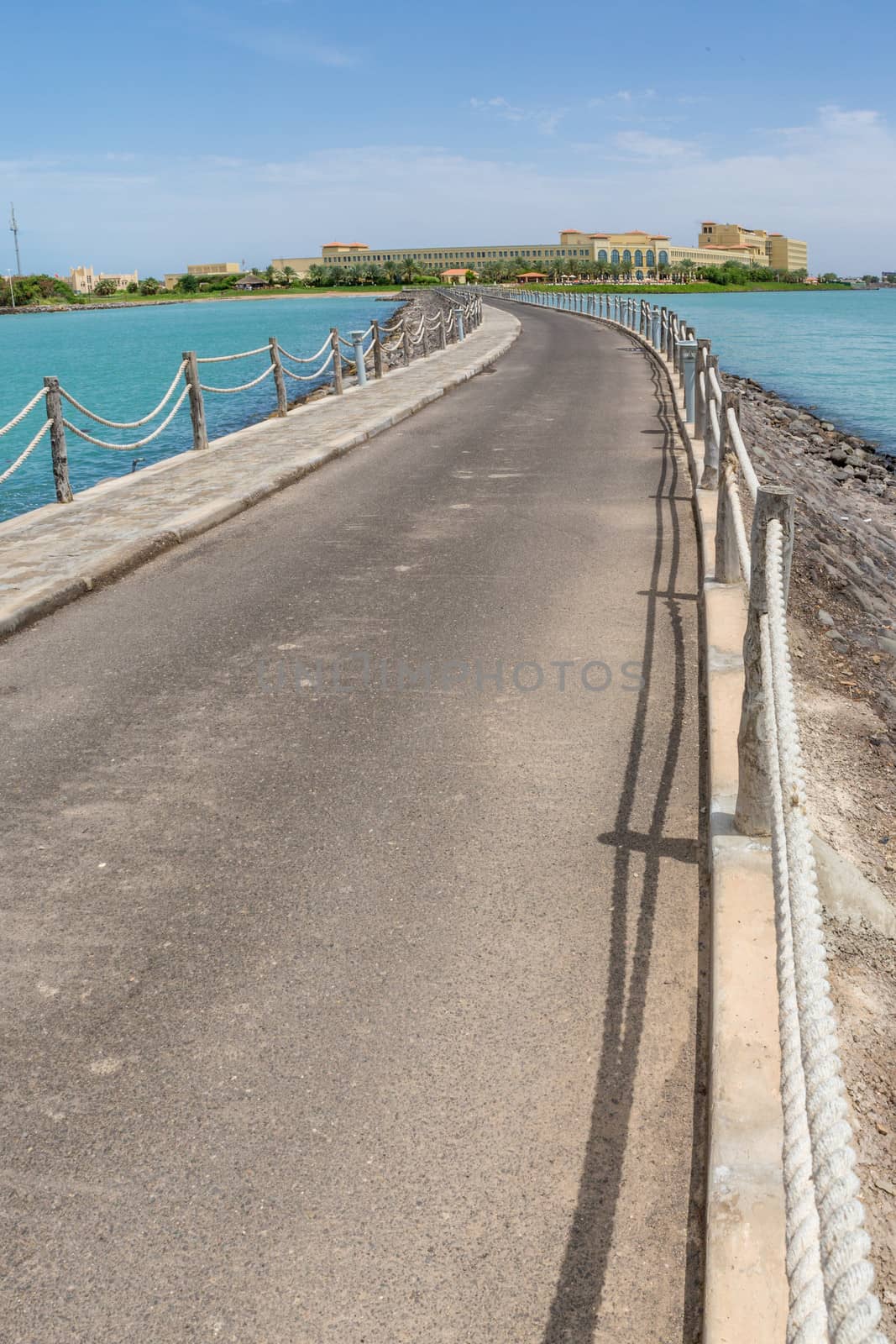 An asphalt walkway fenced with rope along the turquoise waters of the Red sea