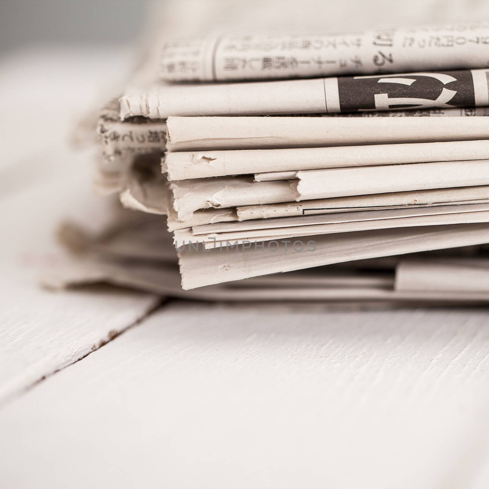 Pile of black and white newspapers on a wooden table