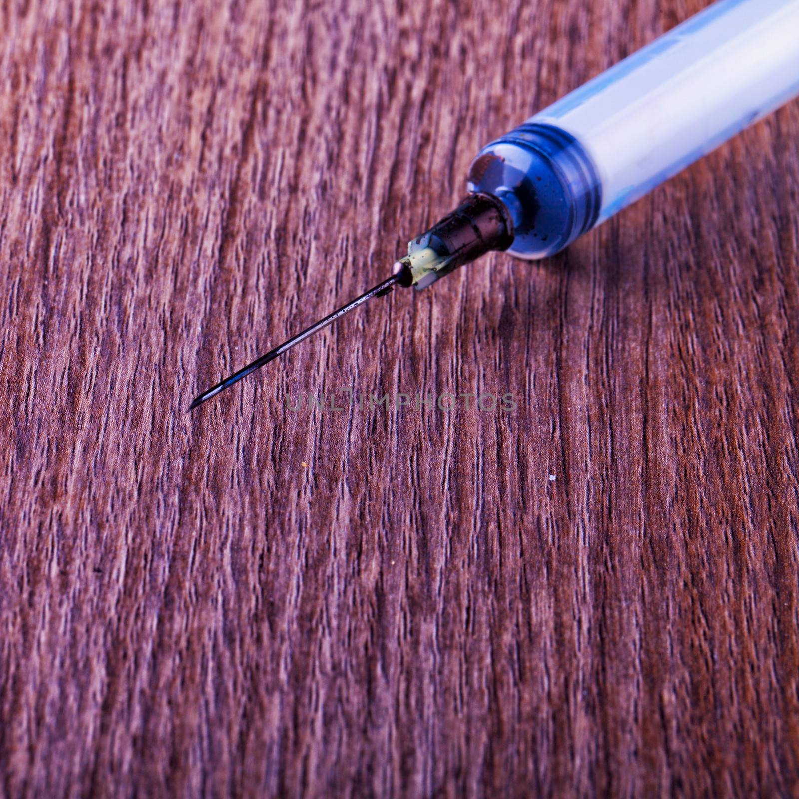 Syringe almost empty over a wooden background