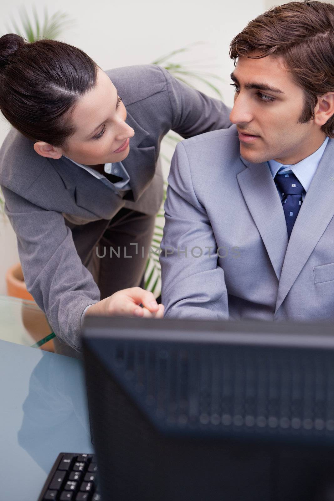 Business man and woman in discussion while using computer at office