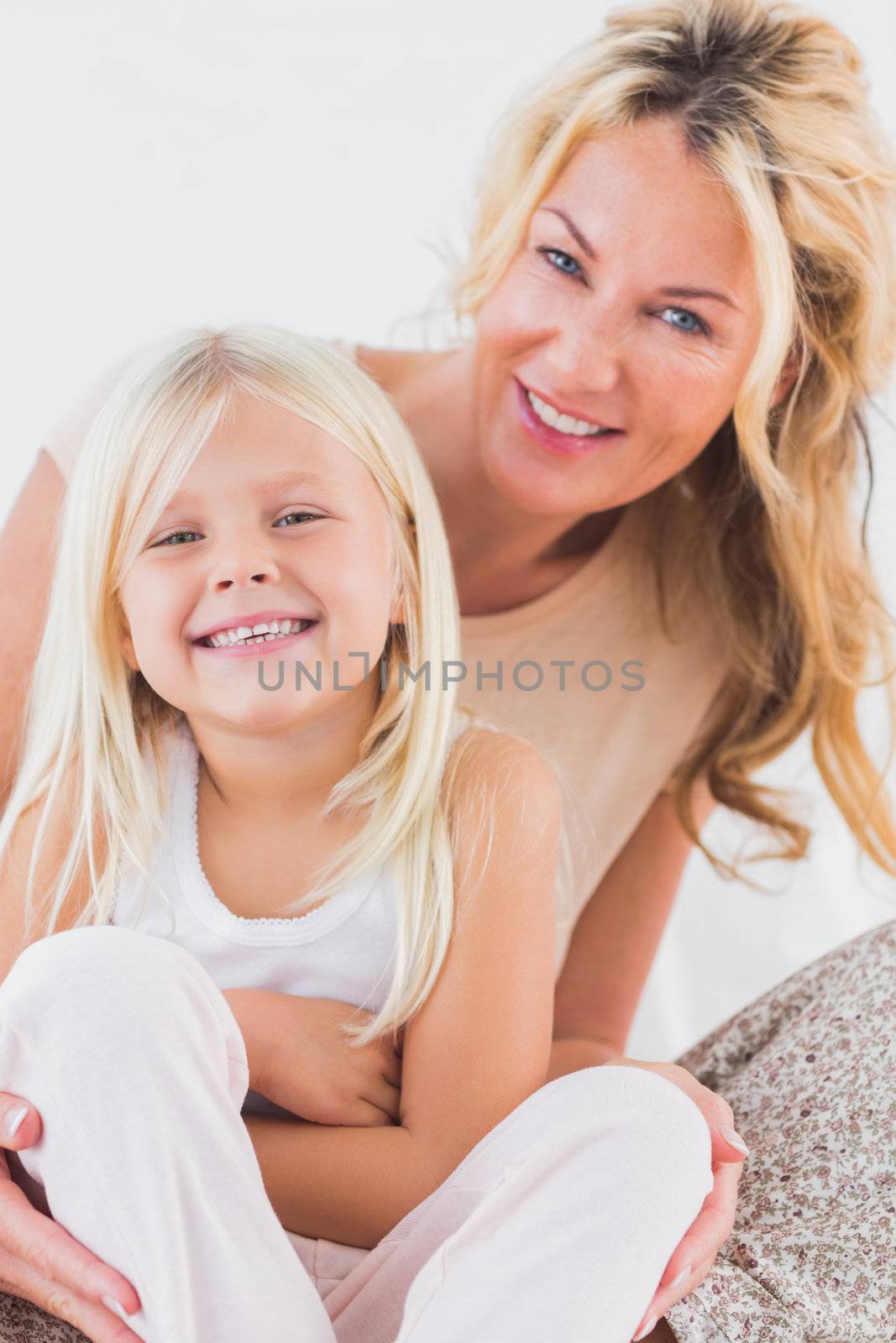 Mother and child sitting on a bed looking at camera