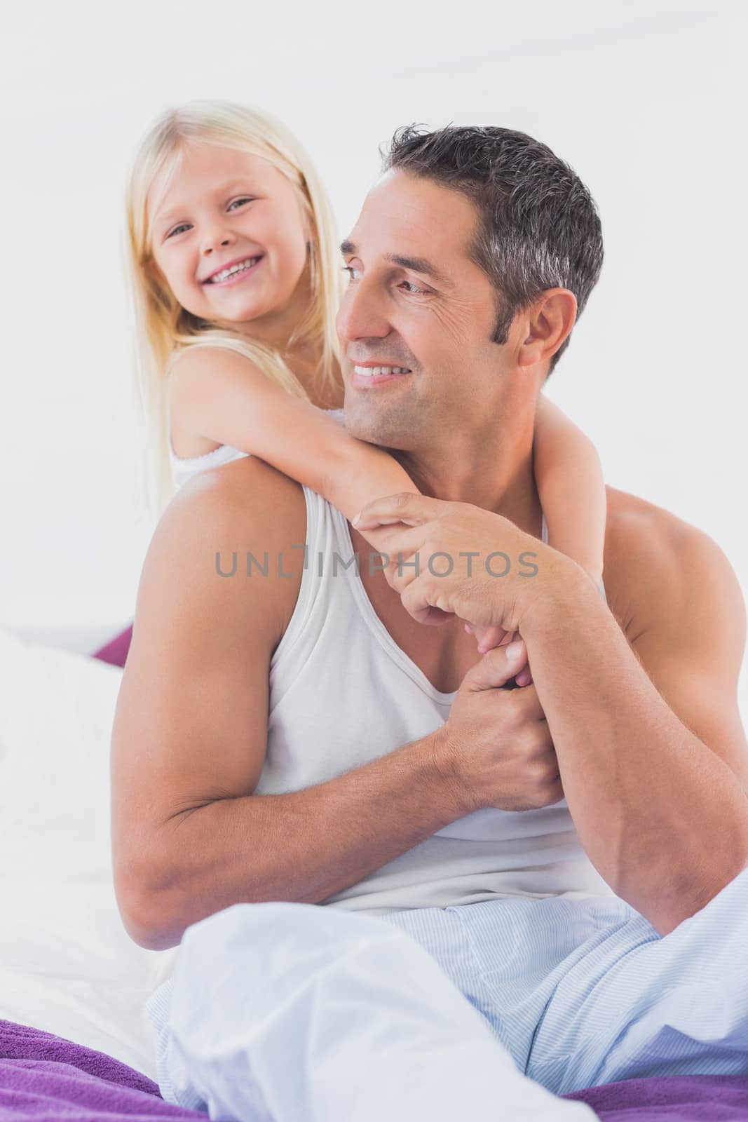 Smiling father and his daughter doing piggyback on a bed in the bedroom